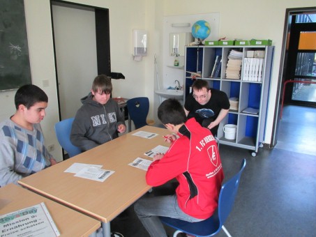 4 Schüler bearbeiten, an einem Tisch sitzend, Arbeitsblätter